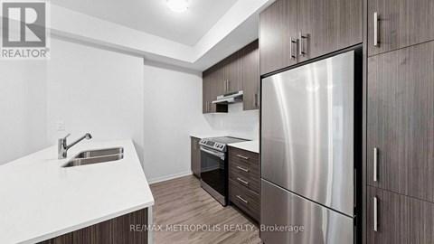 A modern kitchen with a stainless steel refrigerator and wooden cabinets.