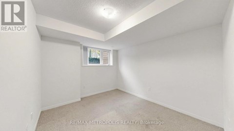 A white bedroom with a window and a carpeted floor.