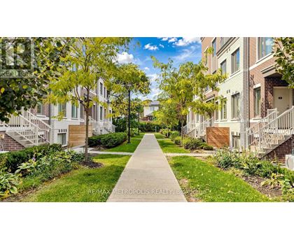 A tree-lined walkway leads to apartment buildings.