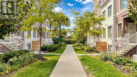 A tree-lined walkway leads to apartment buildings.