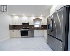 A modern kitchen with stainless steel appliances and white marble flooring.