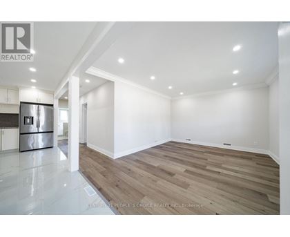 A spacious room with wooden flooring and white walls.