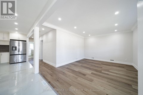 A spacious room with wooden flooring and white walls.