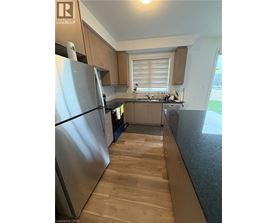 A kitchen with wooden floors and a stainless steel refrigerator.