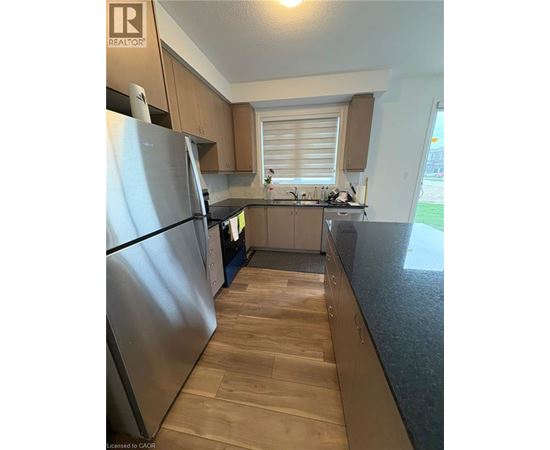 A kitchen with wooden floors and a stainless steel refrigerator.