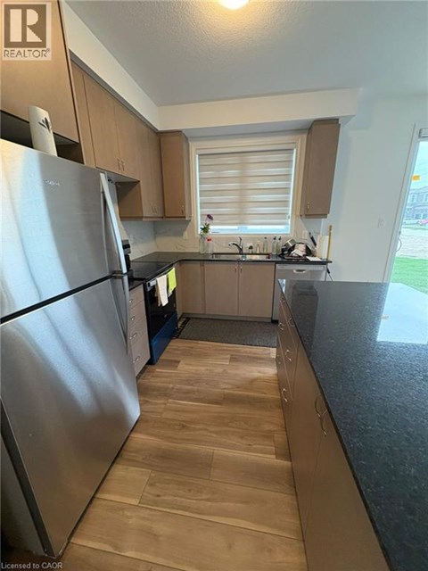 A kitchen with wooden floors and a stainless steel refrigerator.