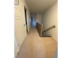 A hallway with a carpeted floor and a staircase.