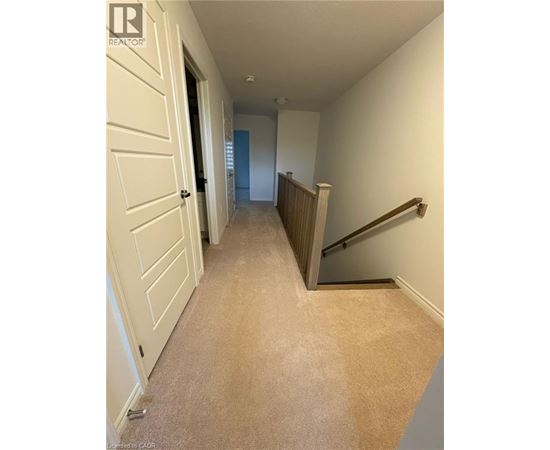 A hallway with a carpeted floor and a staircase.