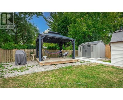 A backyard with a gazebo, a hammock, and a small shed.