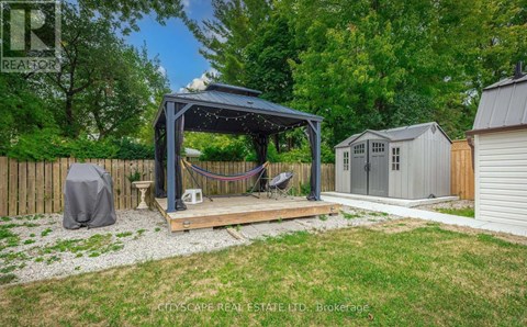 A backyard with a gazebo, a hammock, and a small shed.