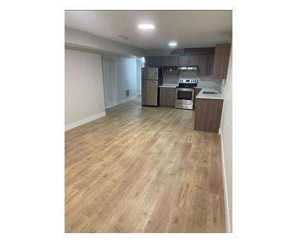 A kitchen with wooden flooring and stainless steel appliances.