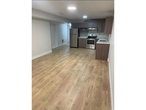 A kitchen with wooden flooring and stainless steel appliances.