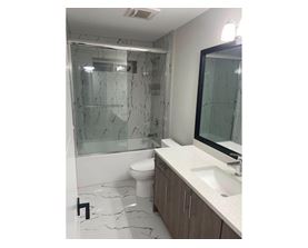 A bathroom with a marble floor and a glass shower stall.