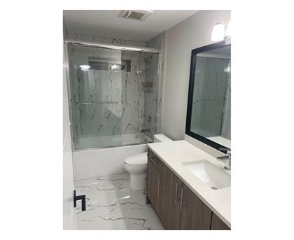 A bathroom with a marble floor and a glass shower stall.