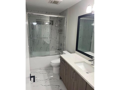 A bathroom with a marble floor and a glass shower stall.