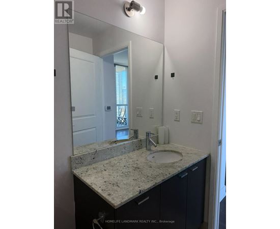A bathroom with a granite countertop and a large mirror.
