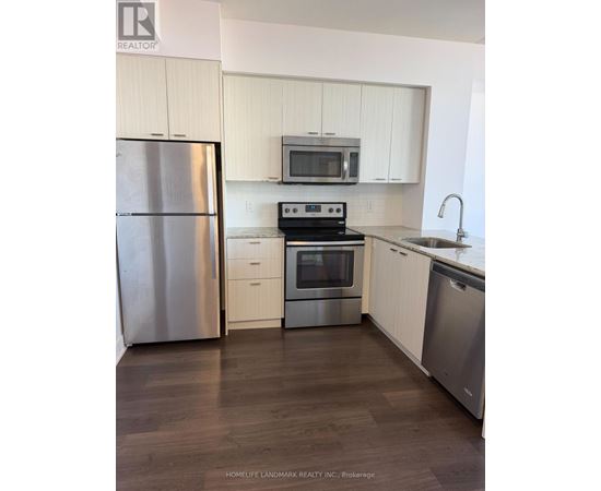 A kitchen with a refrigerator, microwave, oven, and sink.