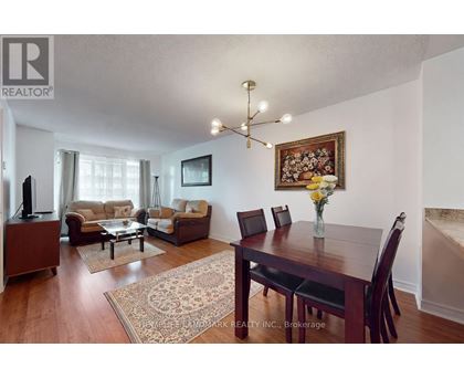 A living room with a brown sofa set and a wooden dining table.