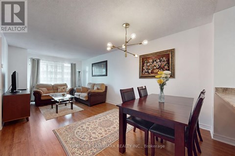 A living room with a brown sofa set and a wooden dining table.