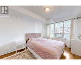 A bedroom with a pink bedspread and a white nightstand.