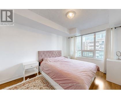 A bedroom with a pink bedspread and a white nightstand.
