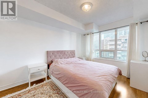 A bedroom with a pink bedspread and a white nightstand.
