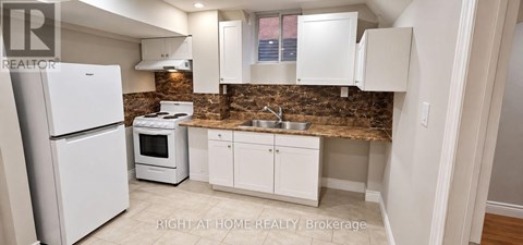 A kitchen with a white refrigerator and cabinets.