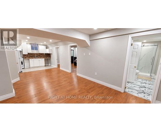 A spacious room with wooden floors and white walls.