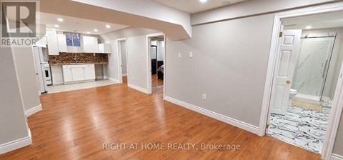 A spacious room with wooden floors and white walls.