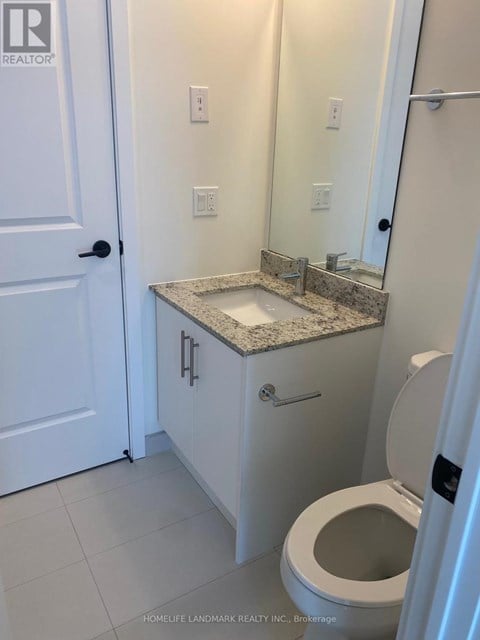 A white bathroom with a toilet, sink, and mirror.
