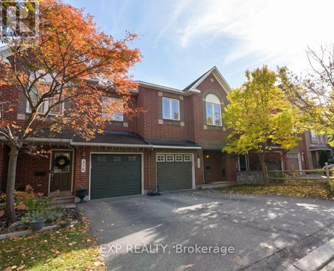 A house with a garage and a tree with orange leaves in front.