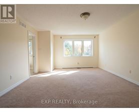 A room with a carpet floor and a window with a view of trees.