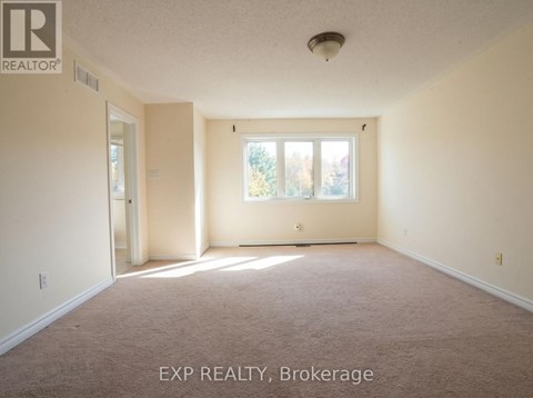 A room with a carpet floor and a window with a view of trees.