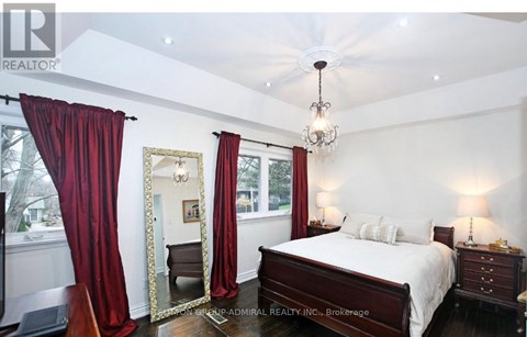A bedroom with a large bed, a chandelier, and red curtains.