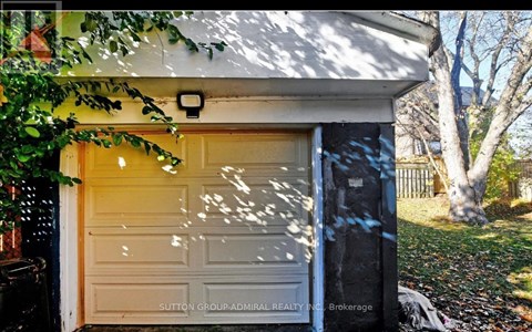 A white garage door is closed and there is a tree in front of it.