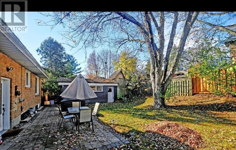 A patio with a table and chairs is surrounded by a brick wall and trees.