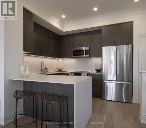A modern kitchen with dark wood cabinets and stainless steel appliances.