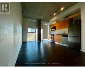 A kitchen area with wooden floors and a stainless steel refrigerator.