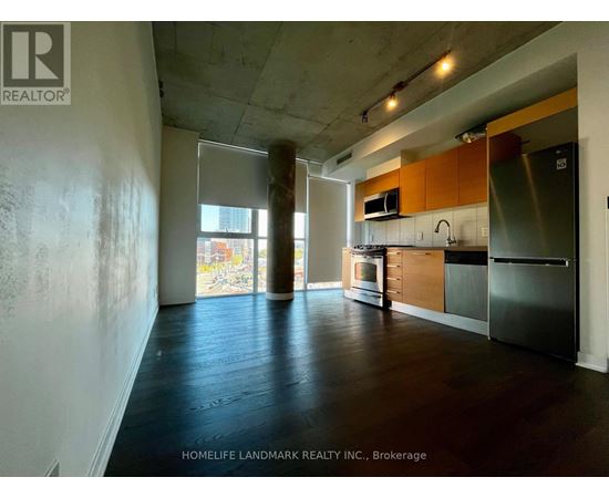 A kitchen area with wooden floors and a stainless steel refrigerator.