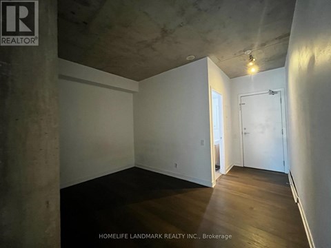 A room with a concrete pillar and wooden flooring.