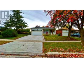 A house with a driveway and a tree with red leaves.