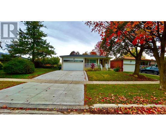 A house with a driveway and a tree with red leaves.