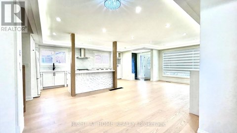 A spacious room with a white ceiling and wooden flooring.