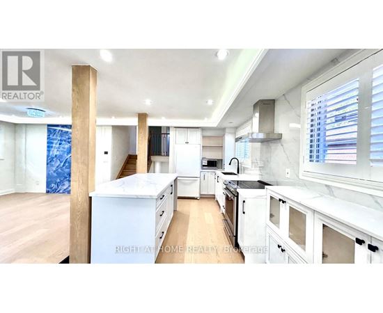 A well-lit kitchen with white cabinets and a wooden floor.