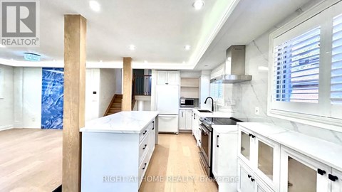 A well-lit kitchen with white cabinets and a wooden floor.