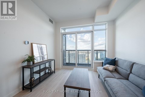 A living room with a grey sofa and a large window.