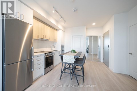 A modern kitchen with a stainless steel refrigerator and a dining table with chairs.