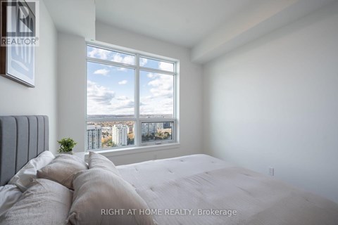 A bedroom with a large bed and a window overlooking a cityscape.