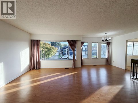 A spacious room with wooden floors and large windows.