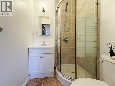A bathroom with a glass shower stall and a white toilet.